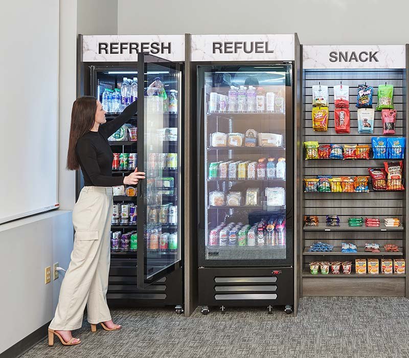 Customer choosing a drink beside refrigerated cabinets and snack shelving