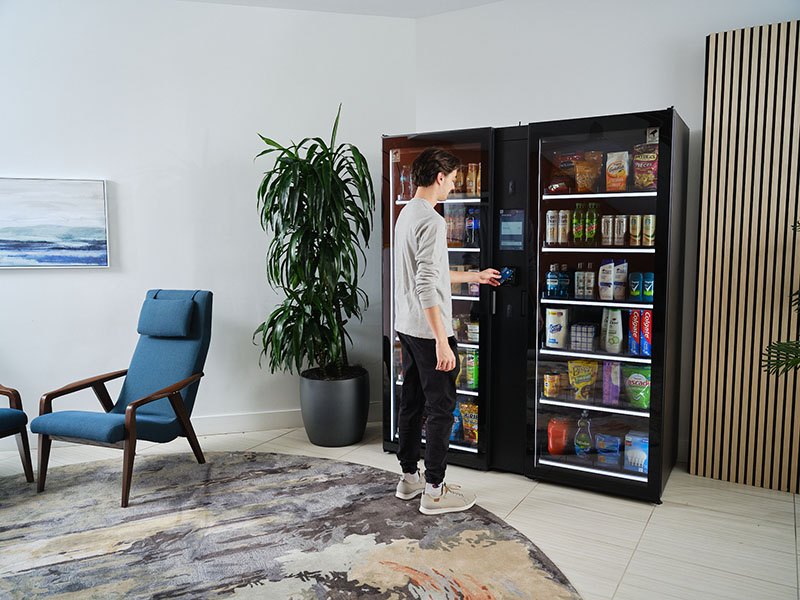 Customer using a payment reader beside stocked smart coolers in a shared lounge